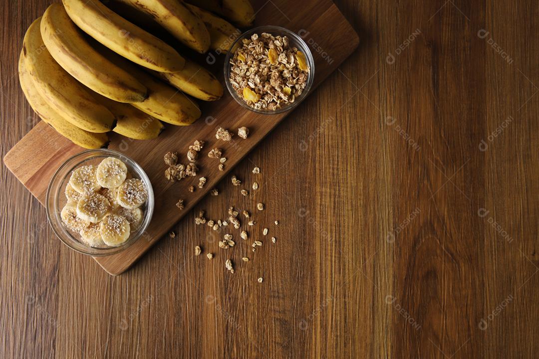 Um banquete de bananas com granola e cereais no fundo de madeira