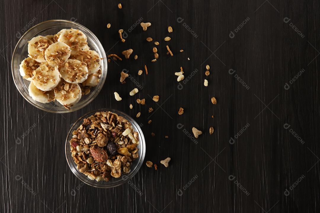 Bananas cortadas em fatias com granola e cereais em cinza escuro woo