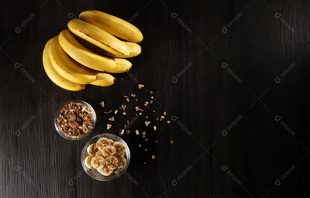 Bananas com granola e cereais, cortadas em fatias em cinza escuro w