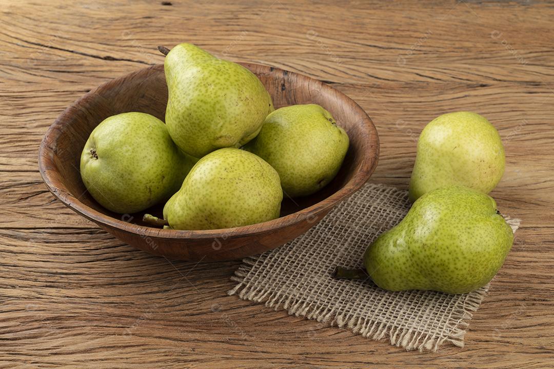 Peras verdes em uma tigela sobre a mesa de madeira.