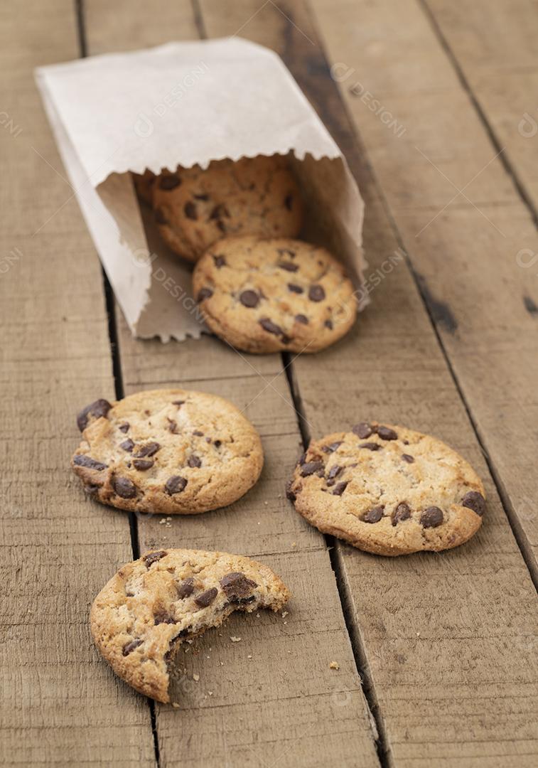 Biscoitos de chocolate em um saco de papel sobre uma mesa de madeira.