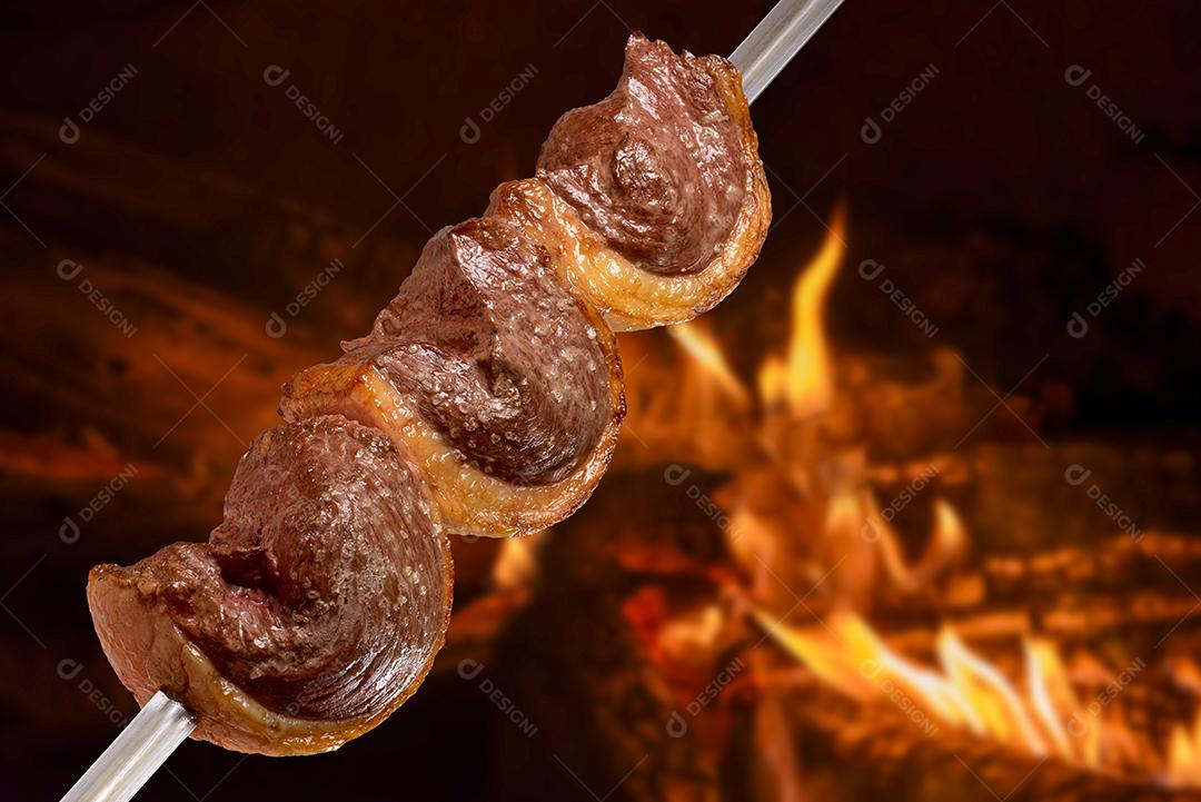 Churrasco de picanha assada no espeto na brasa. Esse tipo de churrasco é amplamente consumido em todo o Brasil