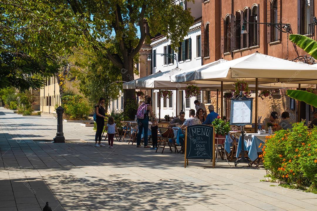 Vista de famílias almoçando em um restaurante típico italiano nas ruas de Veneza.