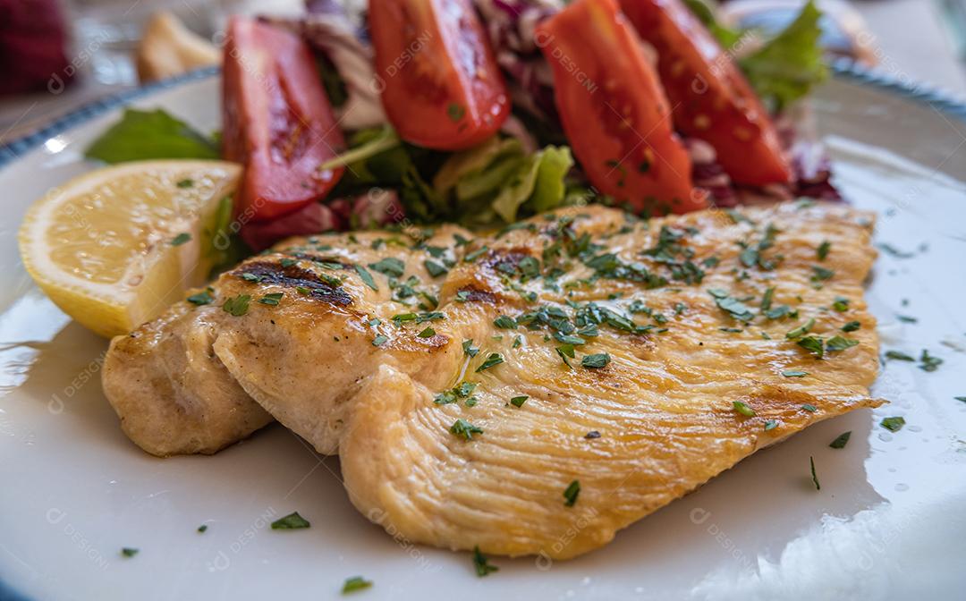 Prato típico italiano de peito de frango com salada de tomate.