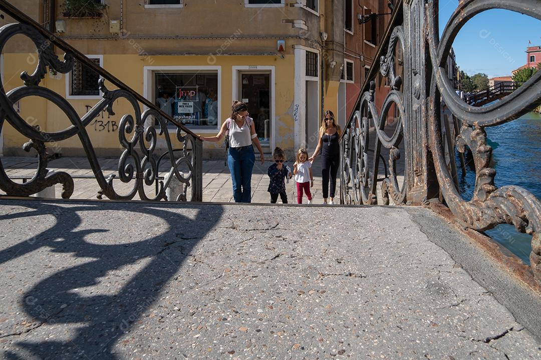 Grupo de mães e filhas caminhando sobre as pontes dos canais de Veneza.