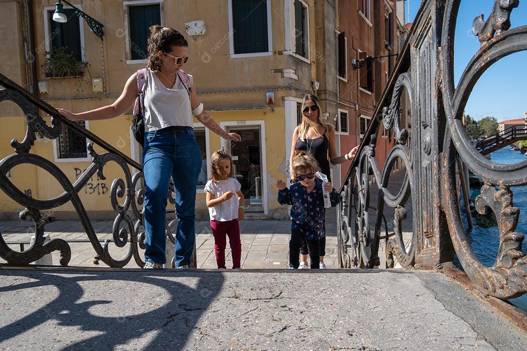 Mães e filhas cruzando a ponte sobre os canais de Veneza