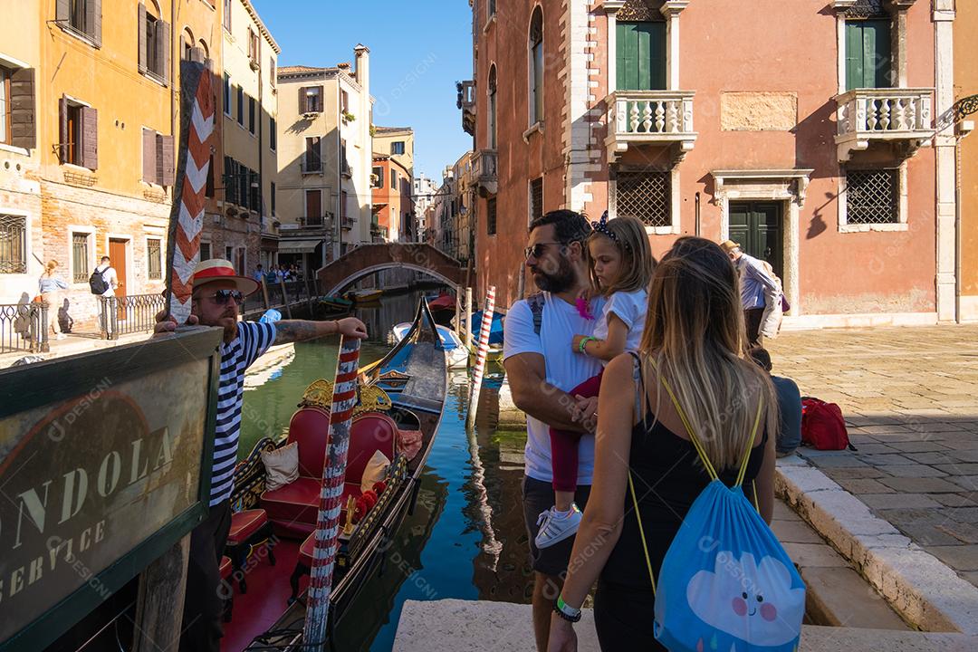 Pai de família negociando com gondoleiro nos canais de Veneza na Itália..