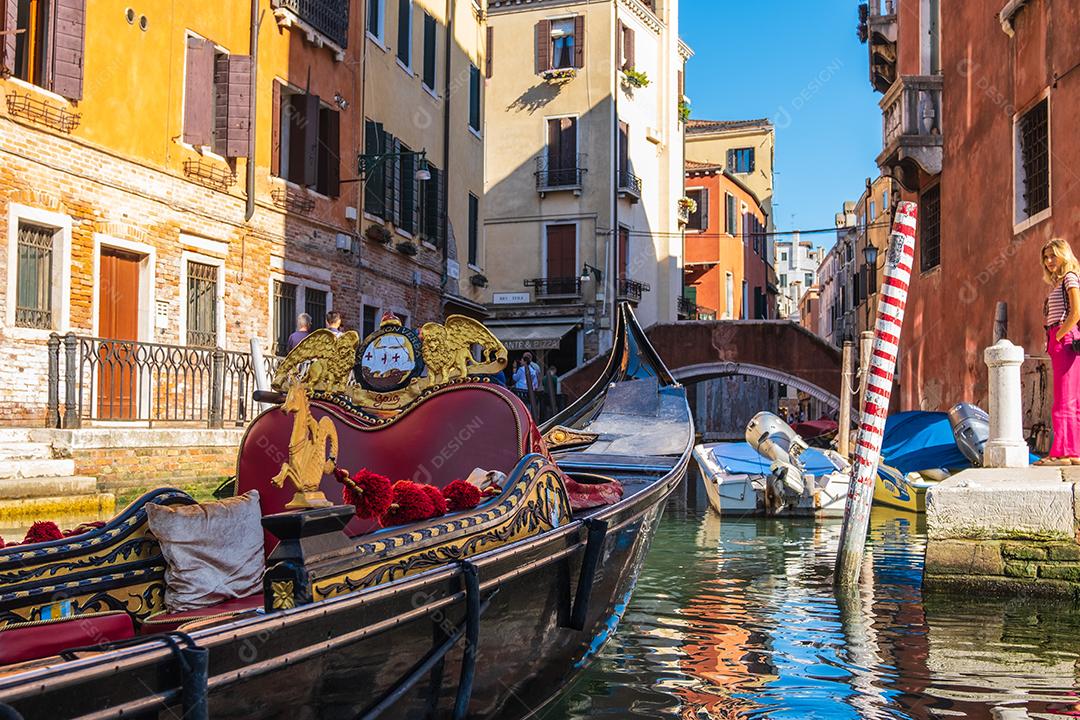 Vista da gôndola vazia em canais estreitos de Veneza com um turista verificando fotos, Itália