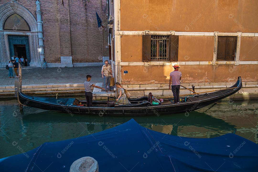 Vista de turistas casal entrando gôndola nos canais de Veneza.