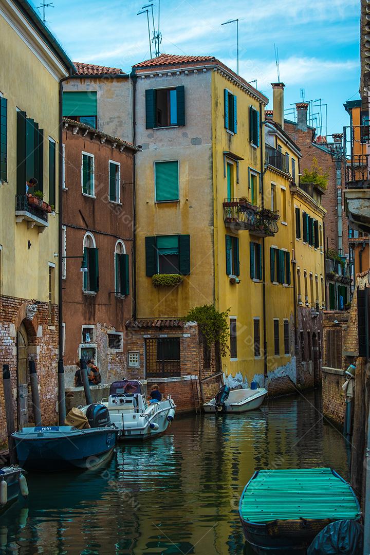 Vista de poucos turistas no estreito canal de Veneza, na Itália, com alguns barcos.