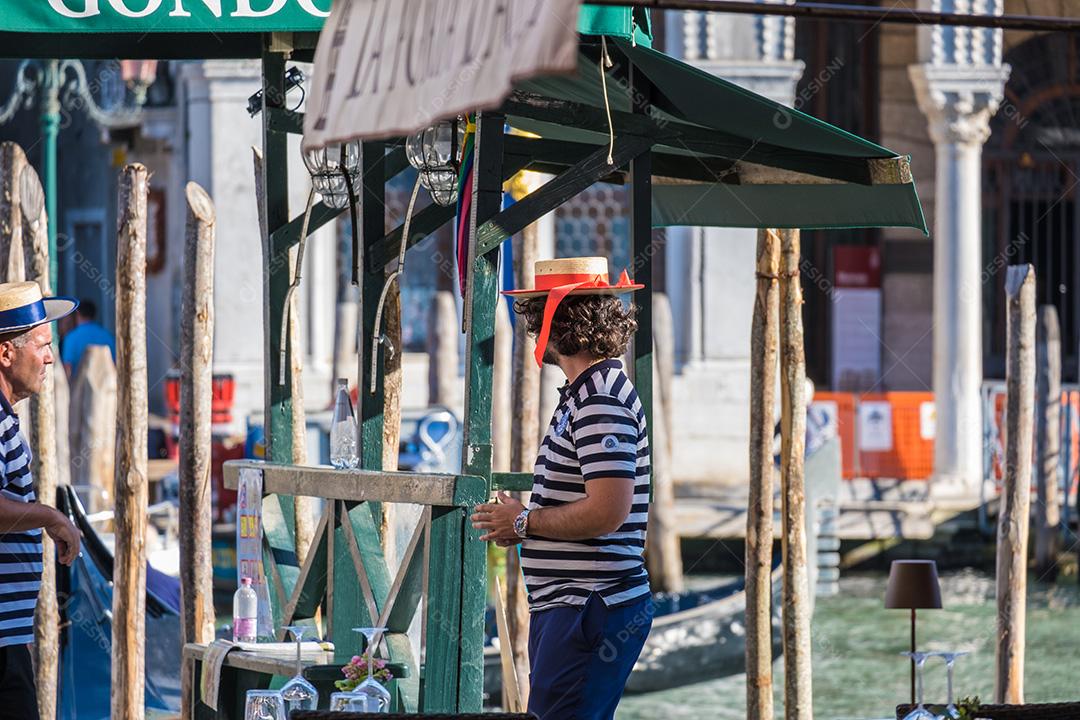 Vista de dois gondoleiros à espera de turistas no ponto de gôndola em Veneza.