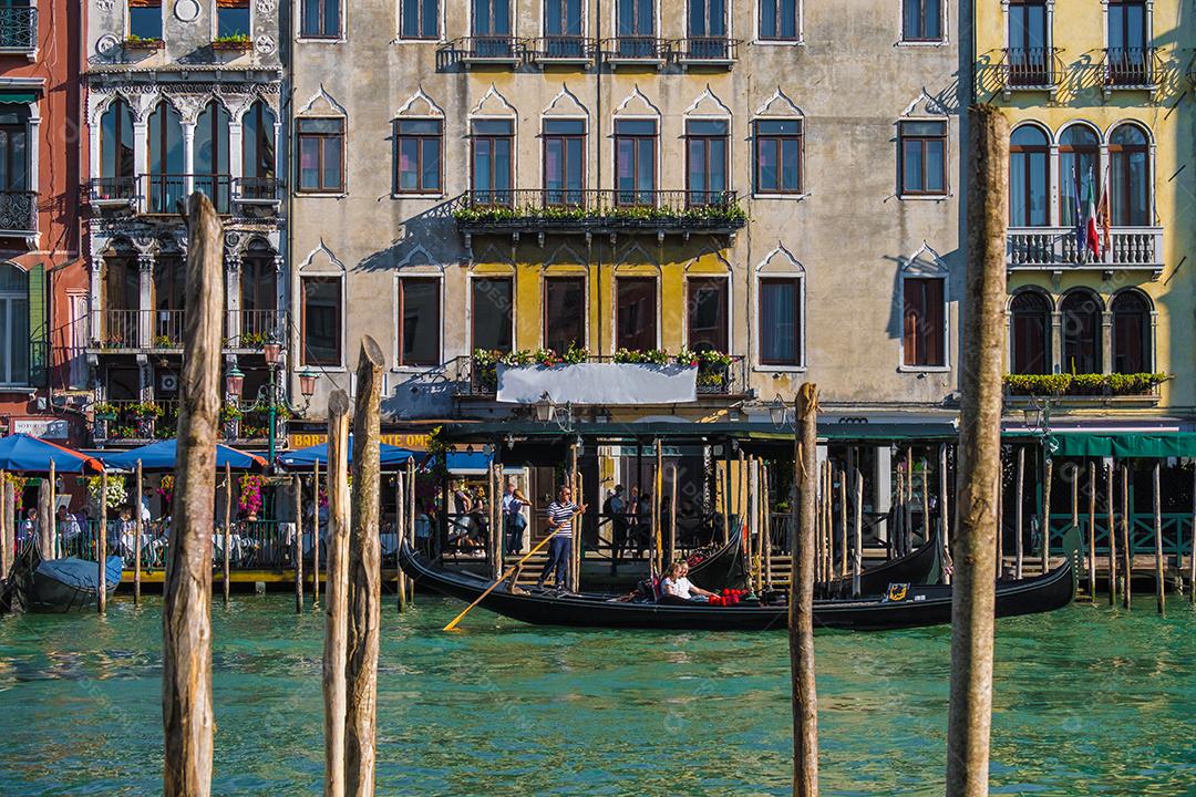 Vista da gôndola levando turistas ao longo do grande canal de Veneza com casas típicas ao fundo