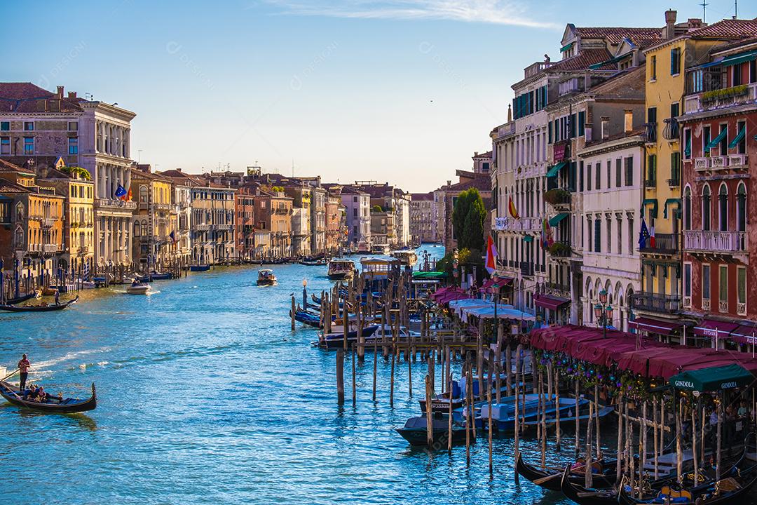 Vista das fachadas de edifícios antigos pitorescos no Grande Canal, gôndolas e barcos em Veneza. Dia de verão ensolarado com céu azul.