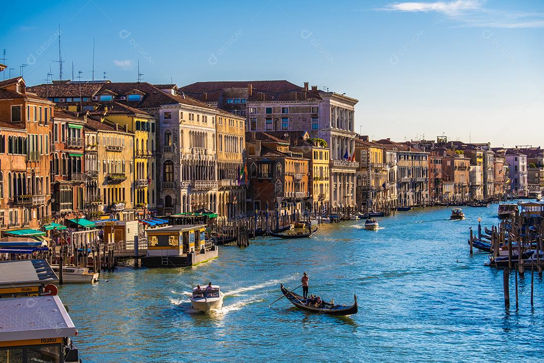 Vista das fachadas de edifícios antigos pitorescos no Grande Canal, gôndolas e barcos em Veneza. Dia de verão ensolarado com céu azul.