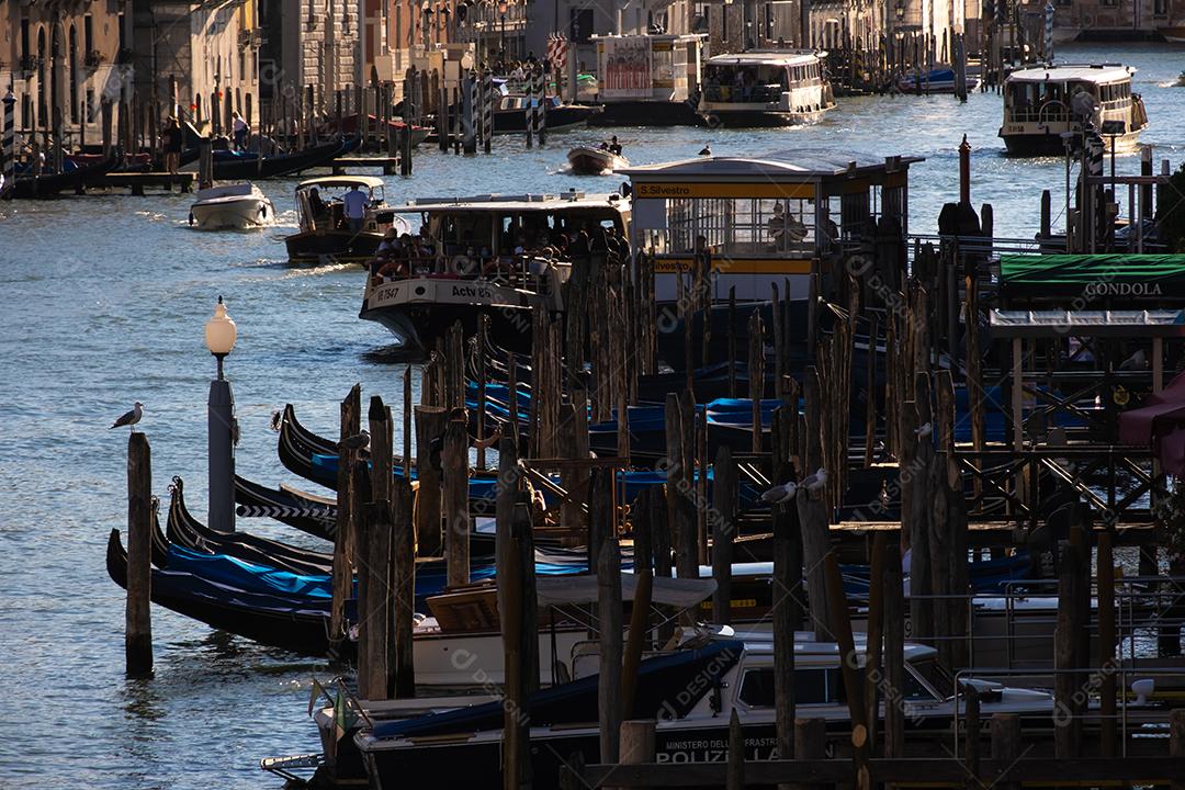 Vista das fachadas de edifícios antigos pitorescos no Grande Canal, gôndolas e barcos em Veneza. Dia de verão ensolarado com céu azul.