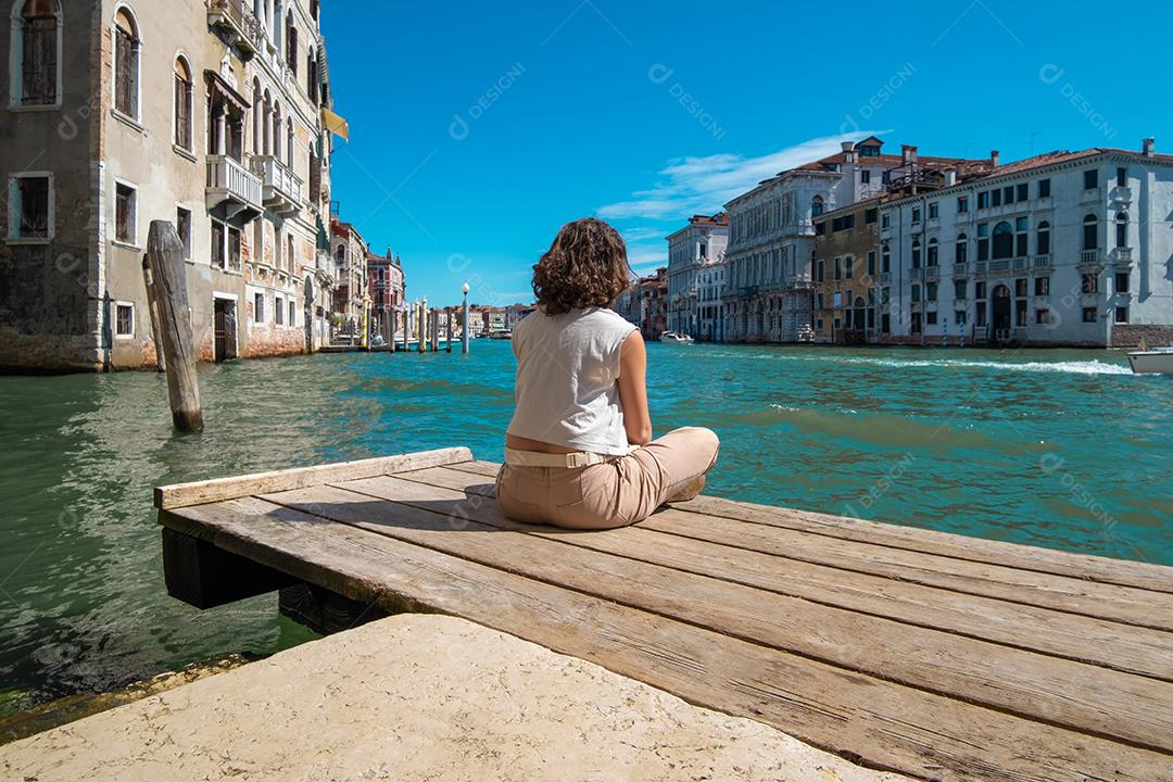 Jovem meditando de frente para os canais de Veneza, na Itália.