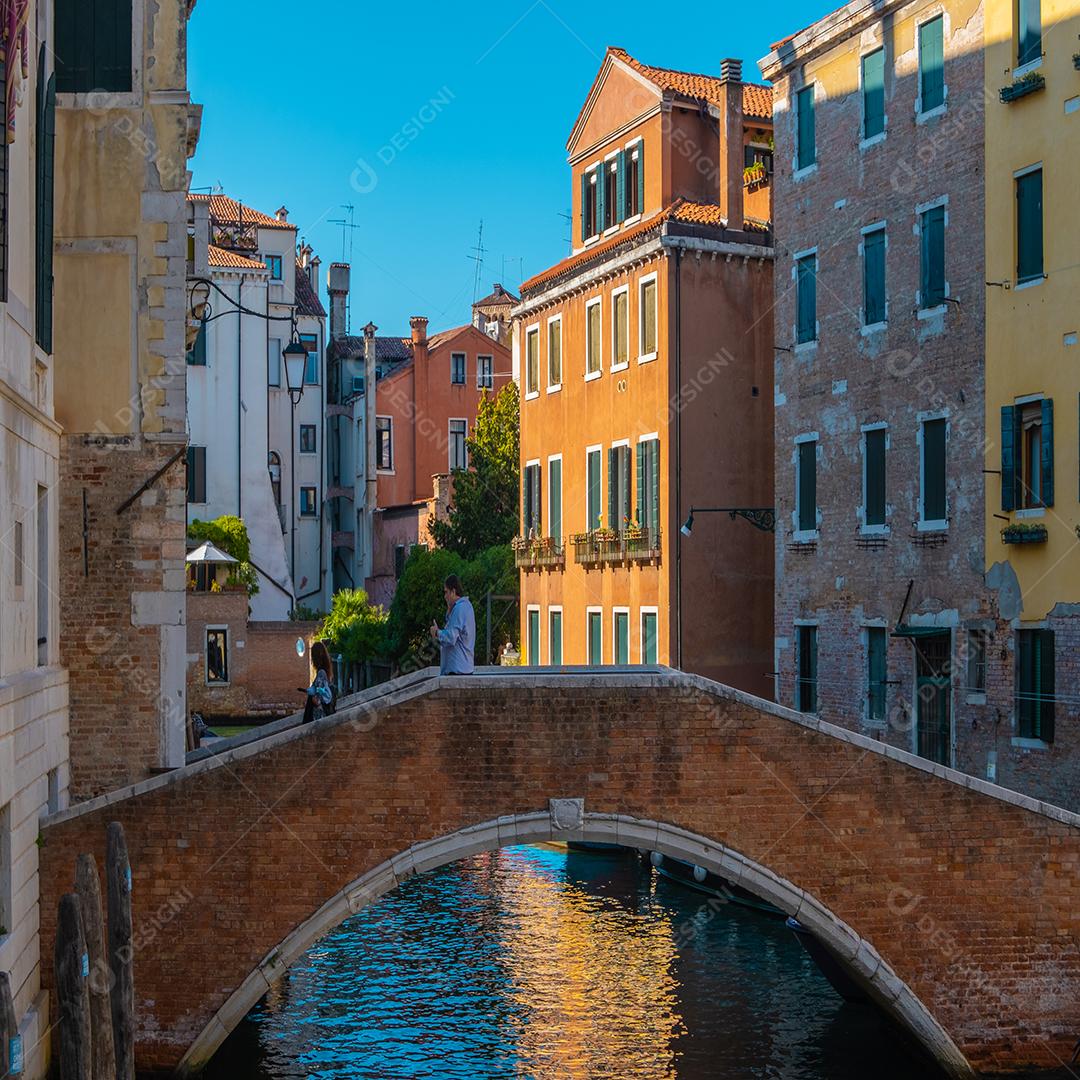 Pessoas andando pela bela ponte sobre os canais de veneza.