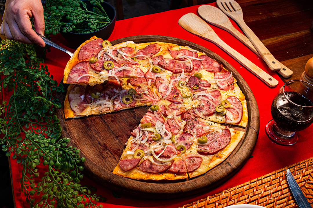 Pizza de calabresa com cebola homem retirando uma fatia