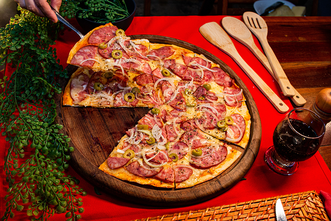 Deliciosa pizza de calabresa com cebola mão retirando fatia