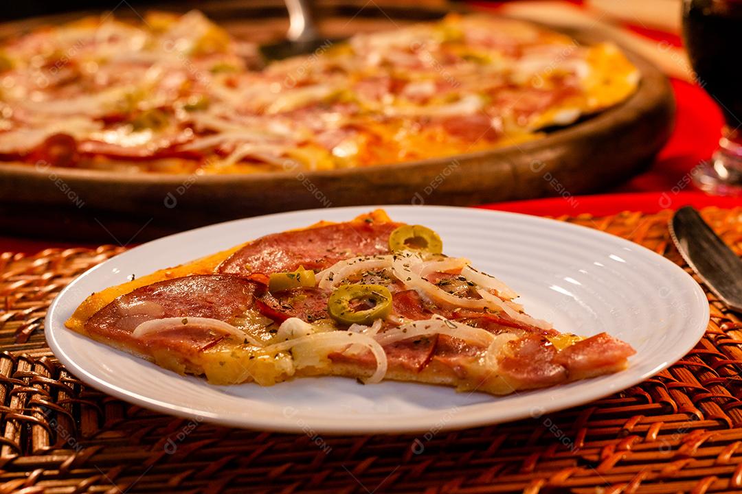 Plate with pizza slice on table next to pizza board