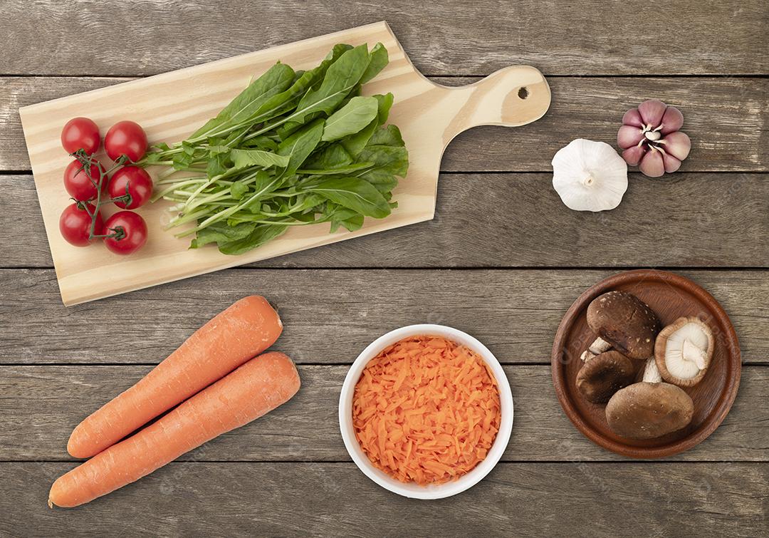 Legumes e ingredientes de salada sobre a mesa de madeira.