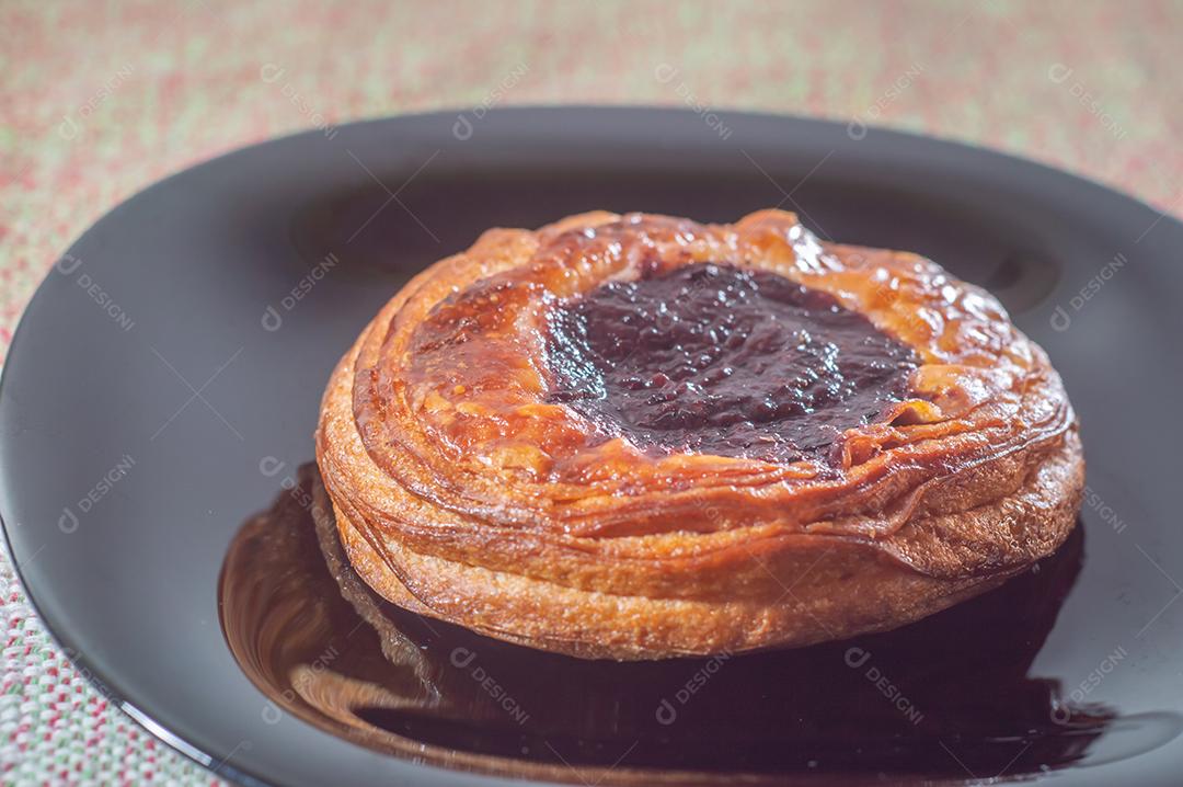 Massa folhada doce recheada com geleia de jabuticaba em prato preto com luz suave.