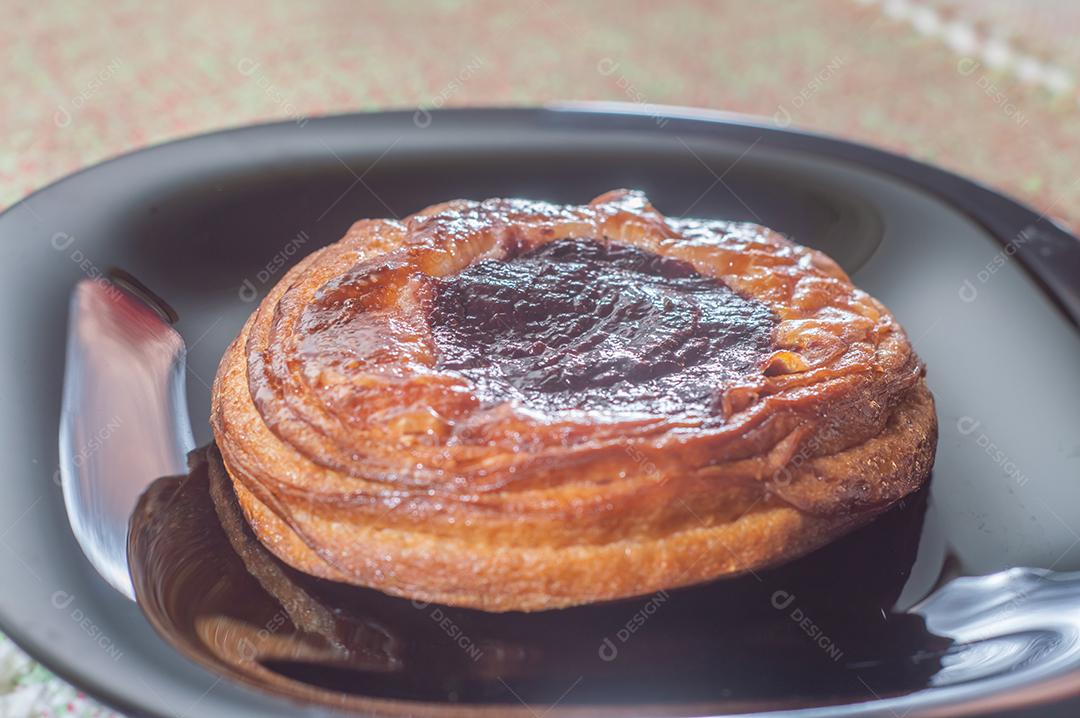 Massa folhada doce recheada com geleia de jabuticaba em prato preto com luz suave.