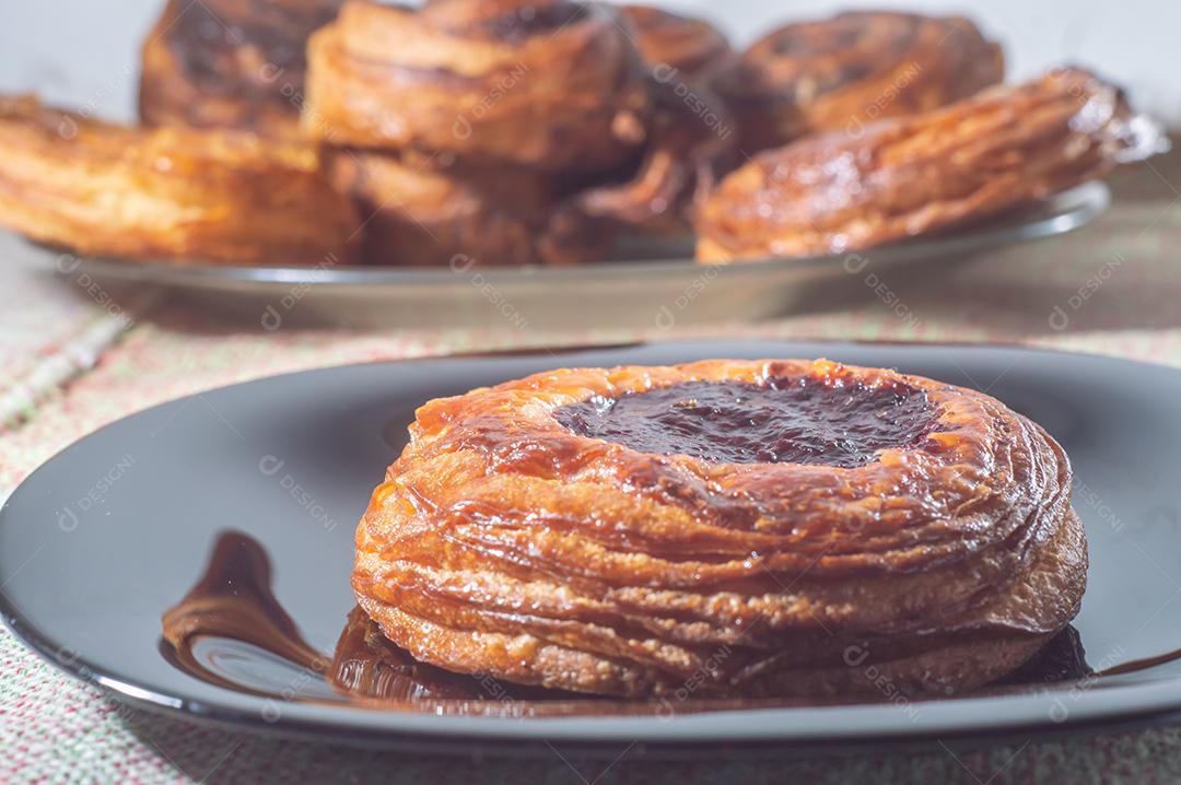 Massa folhada doce recheada com geleia de jabuticaba em prato preto com luz suave.