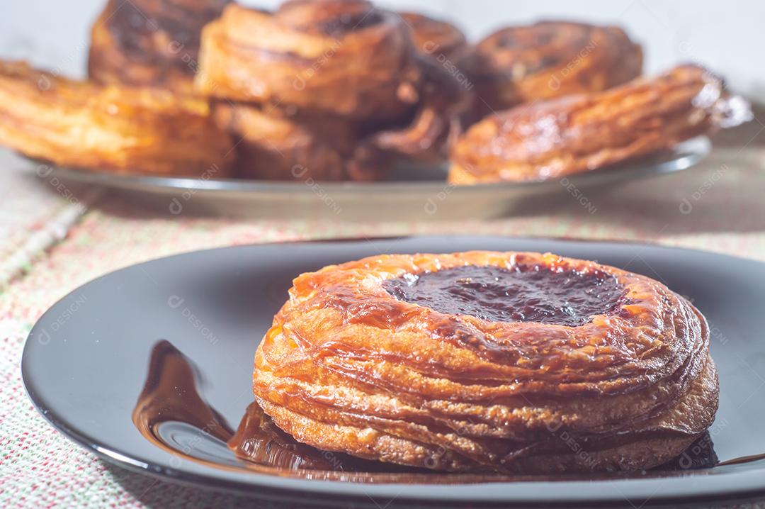 Massa folhada doce recheada com geleia de jabuticaba em prato preto com luz suave.
