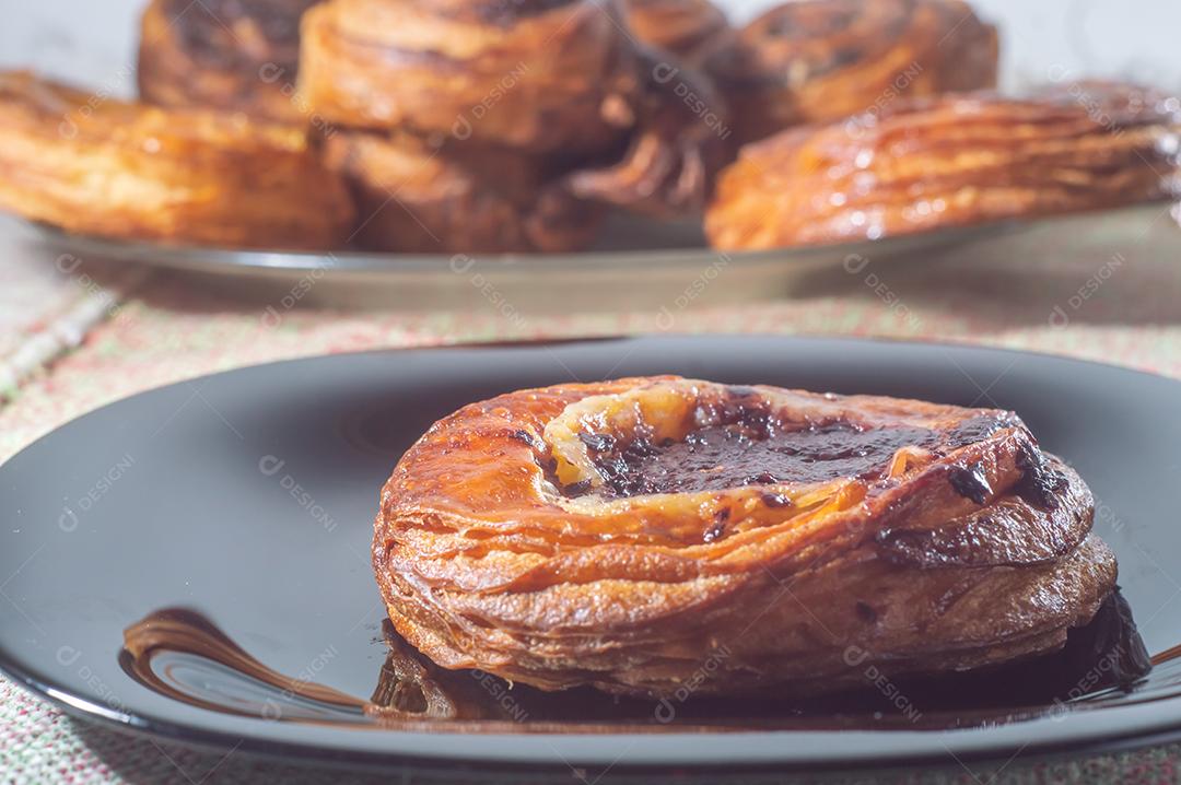 Massa folhada doce recheada com geleia de jabuticaba em prato preto com luz suave.