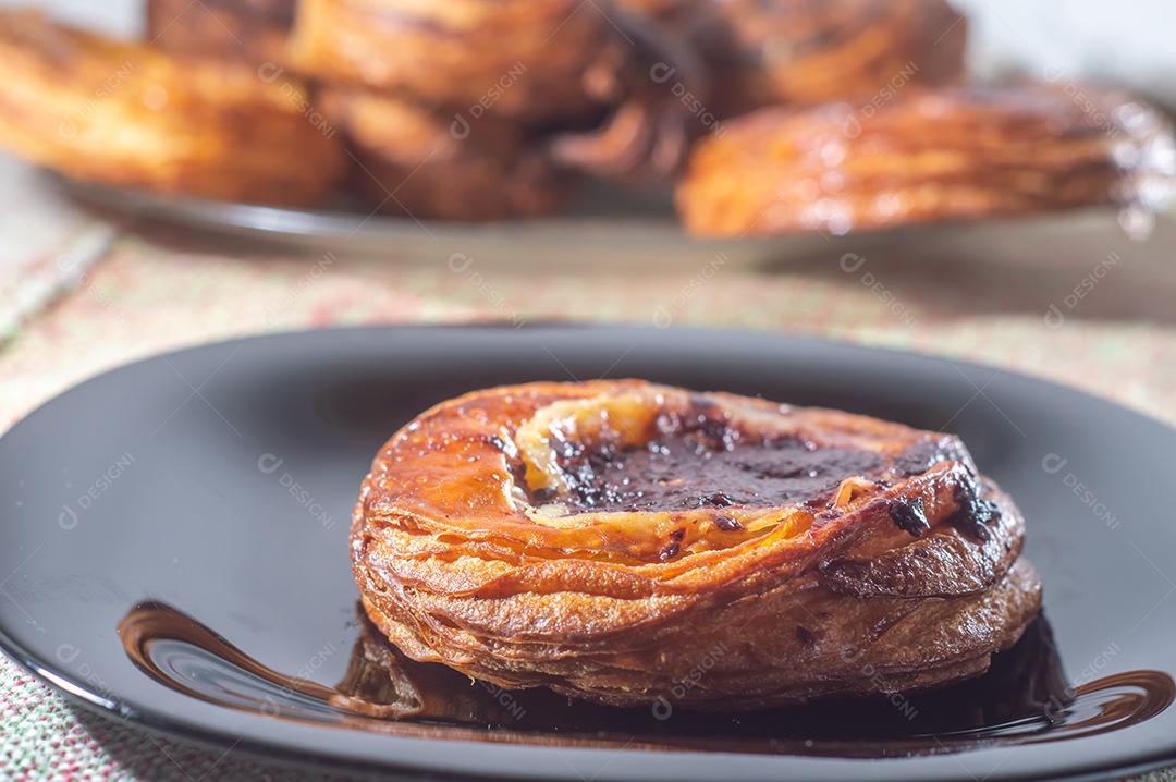 Massa folhada doce recheada com geleia de jabuticaba em prato preto com luz suave.