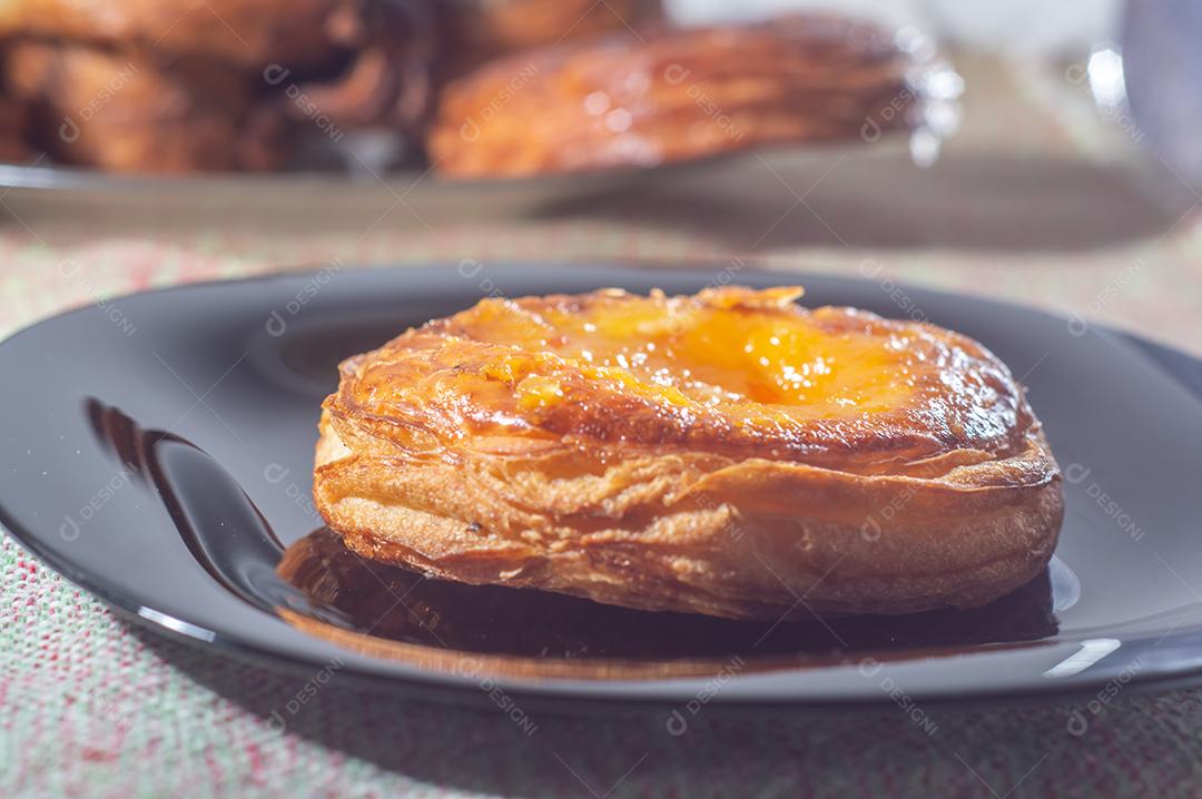 Massa folhada doce recheada com geleia de jabuticaba em prato preto com luz suave.