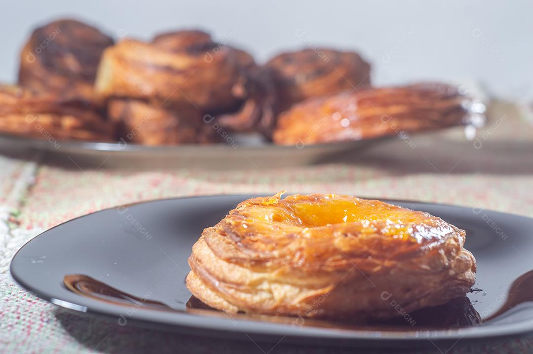 Massa folhada doce recheada com geleia de jabuticaba em prato preto com luz suave.