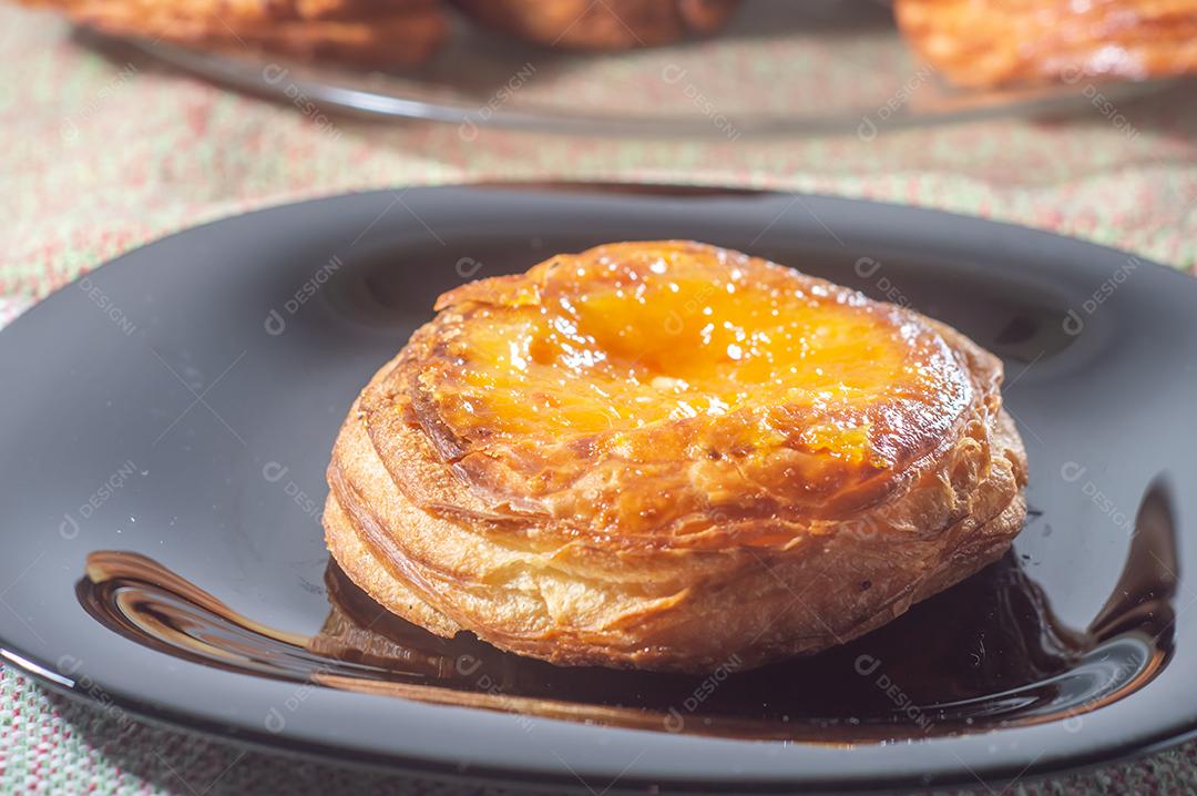 Massa folhada doce recheada com geleia de jabuticaba em prato preto com luz suave.