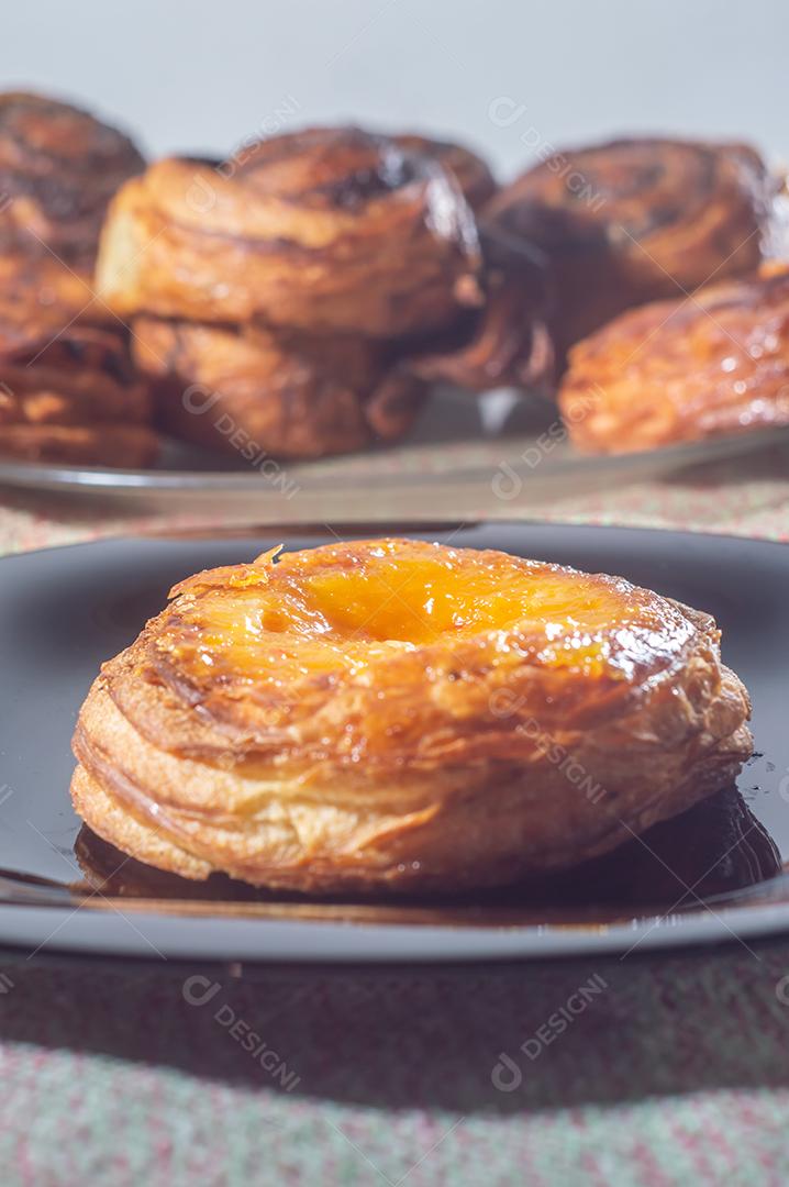 Massa folhada doce recheada com geleia de jabuticaba em prato preto com luz suave.