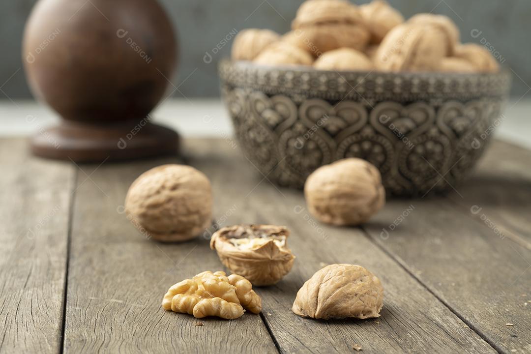 Nozes sobre uma mesa de madeira e em uma tigela.