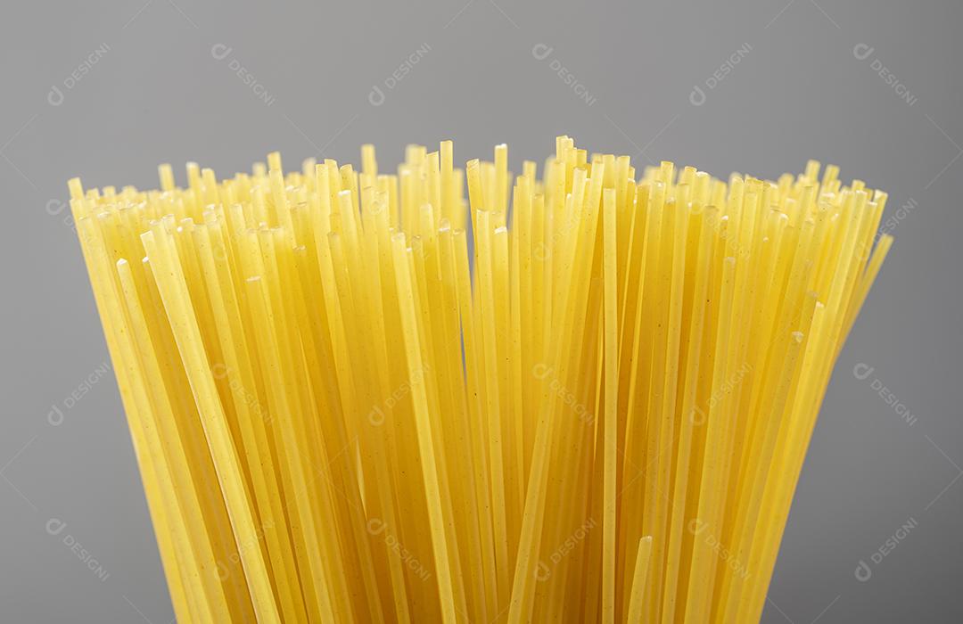 Grupo de macarrão espaguete cru sobre fundo cinza.