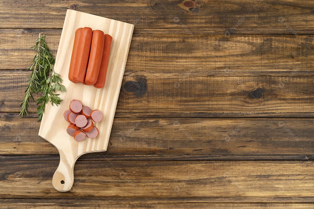 Salsichas e fatias sobre uma placa de madeira