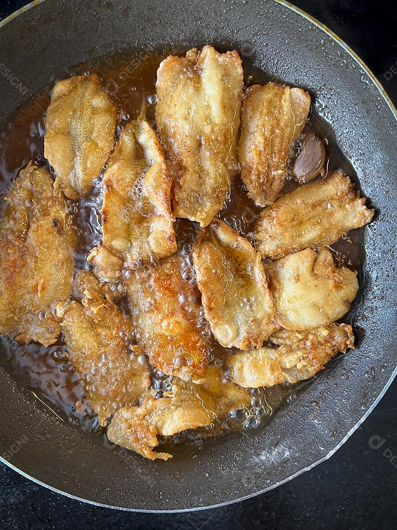 Peixe sendo frito em uma panela com óleo. Comida frita.