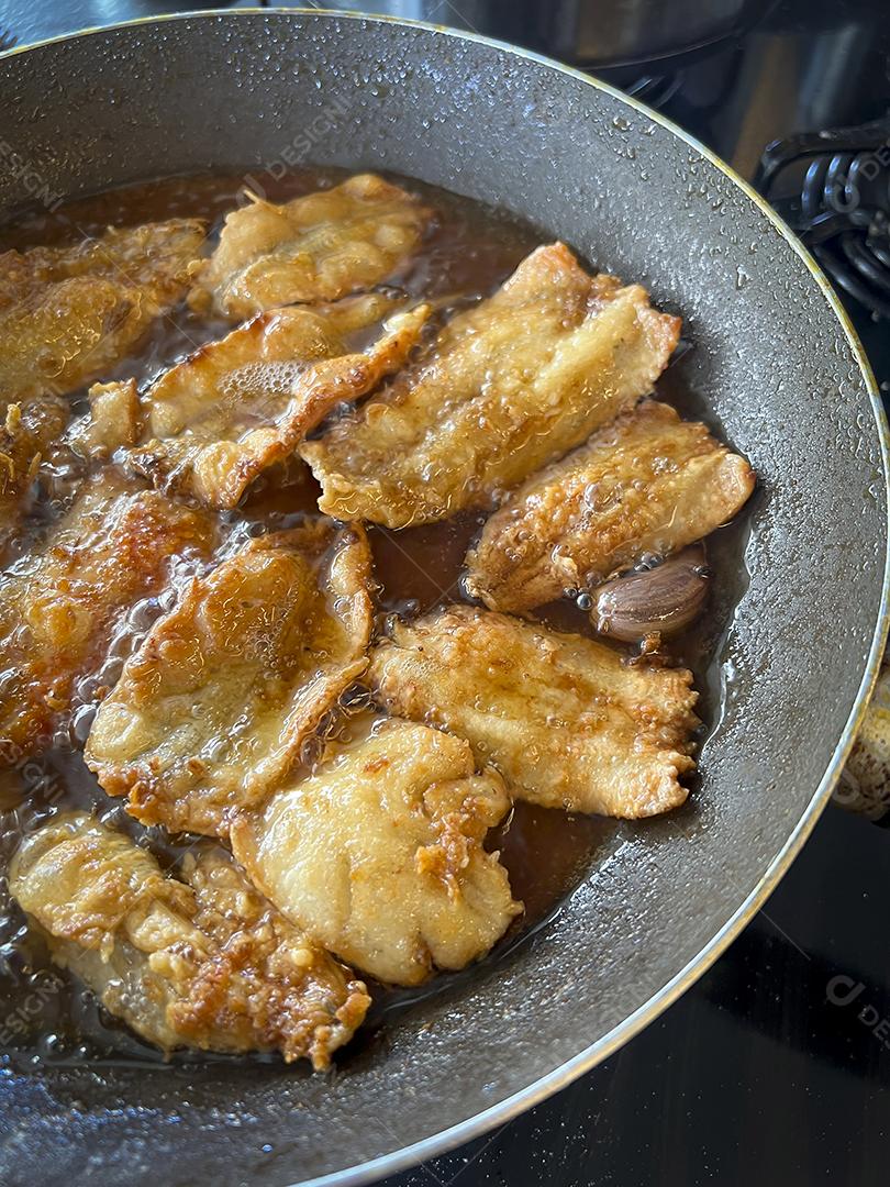 Peixe sendo frito em uma panela com óleo. Comida frita.