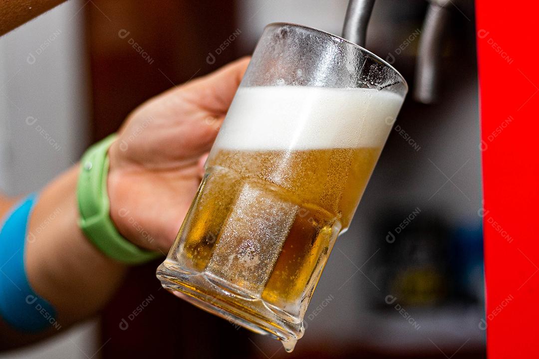 Pessoa enchendo copo com cerveja chopp