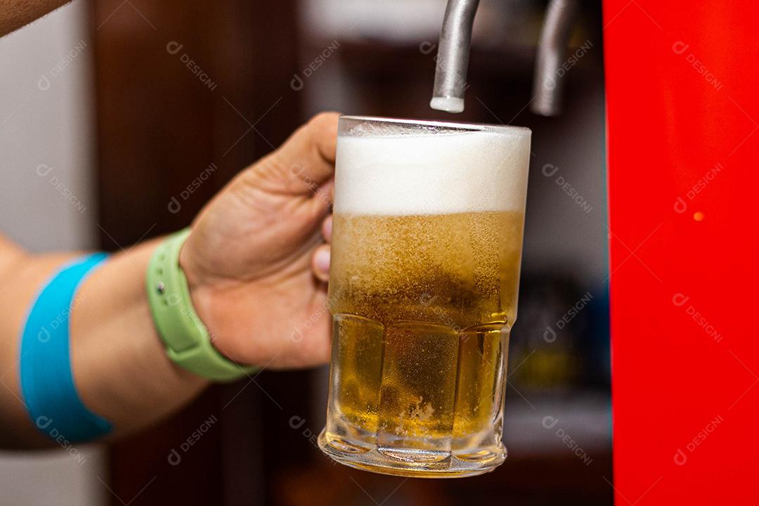 Pessoa enchendo copo com cerveja chopp