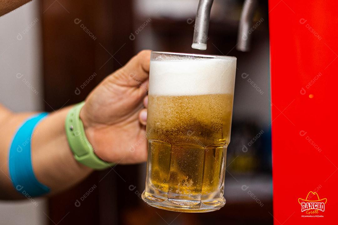 Pessoa enchendo copo com cerveja chopp