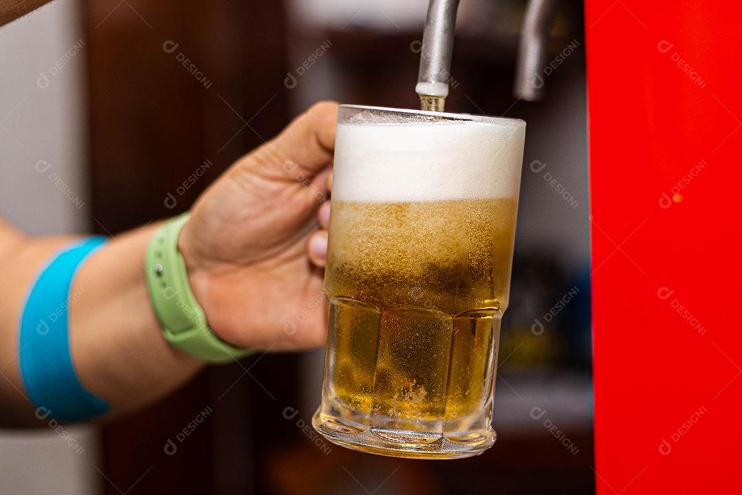 Pessoa enchendo copo com cerveja chopp