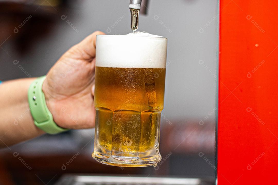 Pessoa enchendo copo com cerveja chopp