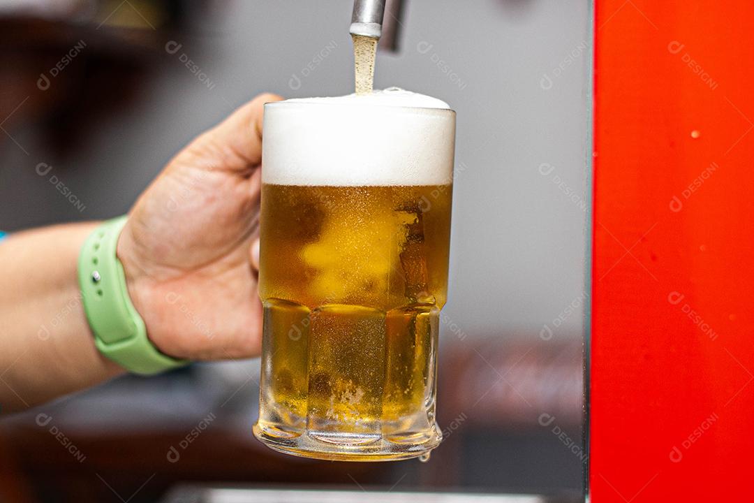 Pessoa enchendo copo com cerveja chopp