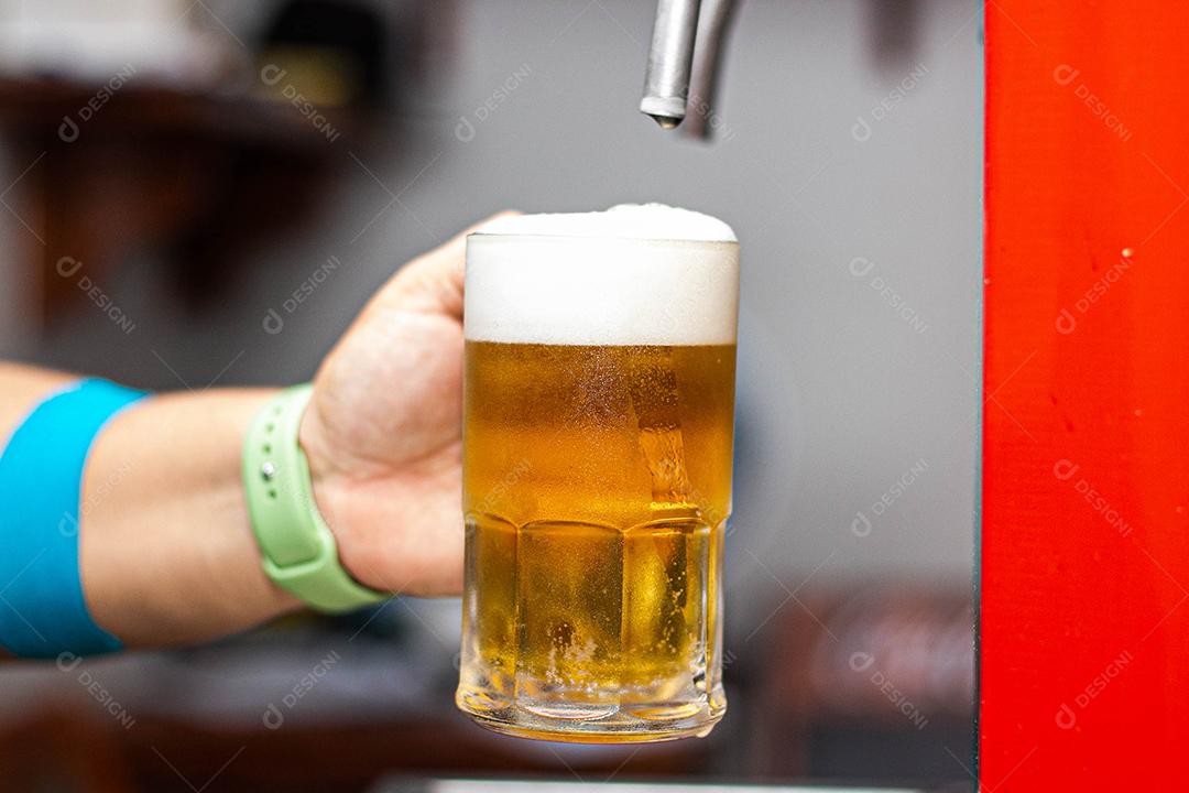 Pessoa enchendo copo com cerveja chopp