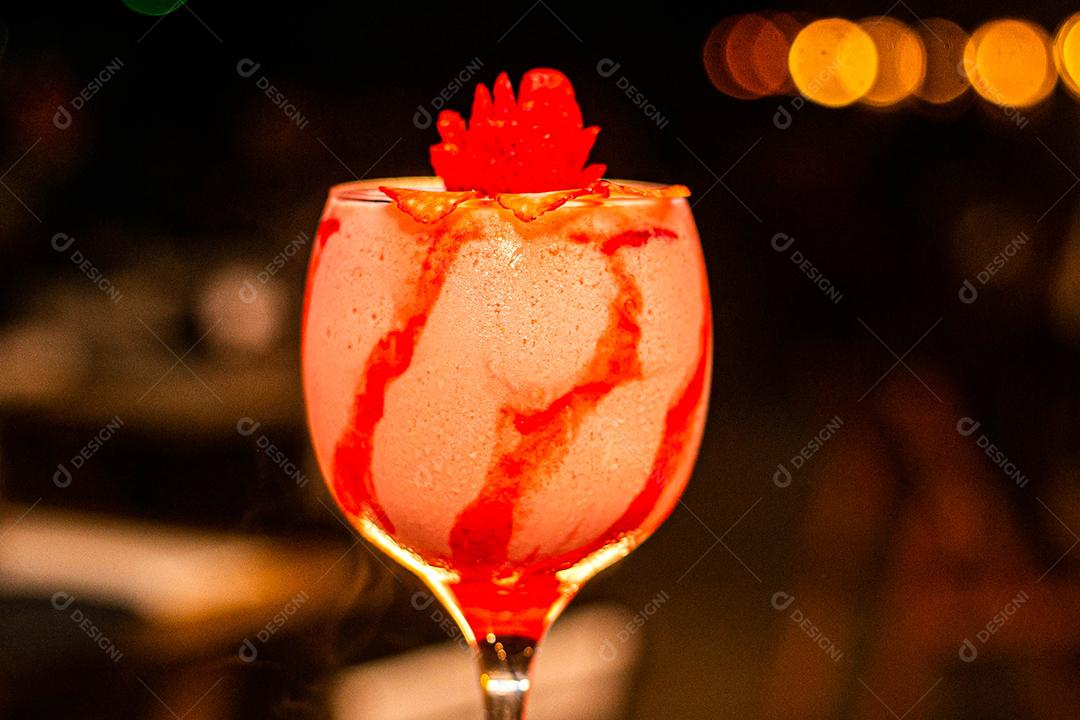 Taça de vidro com bebida rosa de morango com cobertura vermelha