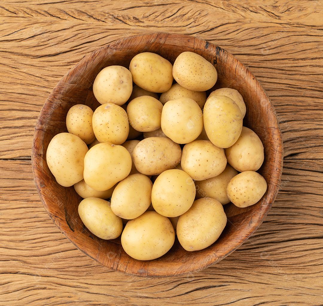 Batatas minúsculas em uma tigela sobre a mesa de madeira.