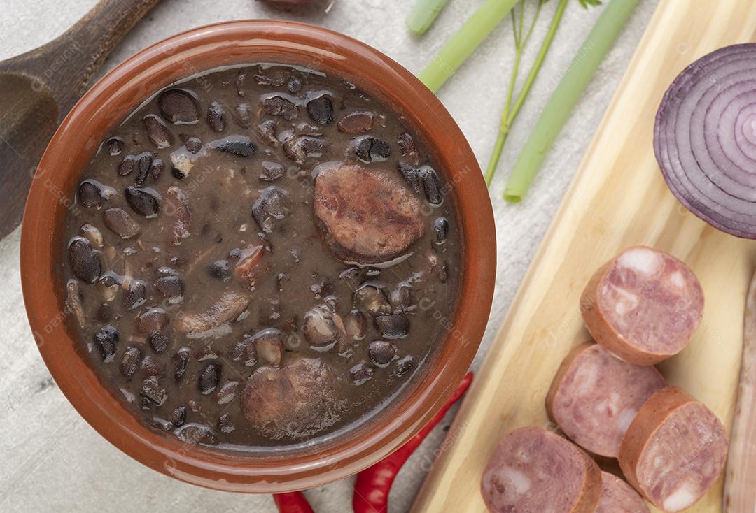 Feijoada tradicional brasileira em uma tigela com ingredientes.